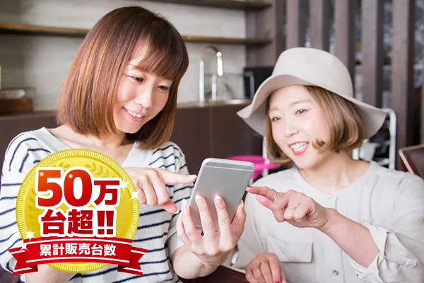 pictur of two girls talking and pointing at a phone